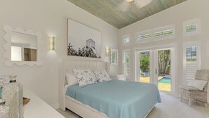 Ein Schlafzimmer mit einem Bett, einem großen Fenster, einer Tür zu einem Balkon und einem Sessel.