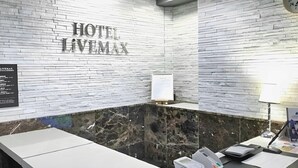 A hotel lobby with a marble reception desk, a clock, and a wall-mounted sign reading 'HOTEL LIVEMAX'. - Hotel Livemax Budget Nagoya Taiko Doriguchi (Nagoya)