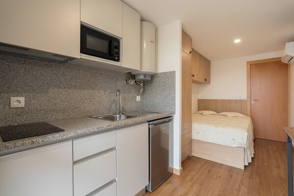 A compact kitchen with a microwave, dishwasher, and granite countertop. - Eco-Bungalow Vista Serra da Estrela (Seia)