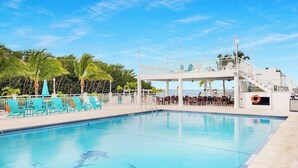 A swimming pool with lounge chairs and a covered area with stairs. - Coral Dolphin Cottage- Waterfront tiny home getaway in Key Largo (Key Largo)
