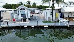 Une propriété située au bord de l’eau, dotée d’un patio couvert, d’un espace salon extérieur et d’un petit bâtiment comprenant un garage.