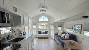 A spacious kitchen with a central island, a dining area with a bench, and a cozy seating area with a sofa. - Coral Dolphin Cottage- Waterfront tiny home getaway in Key Largo (Key Largo)