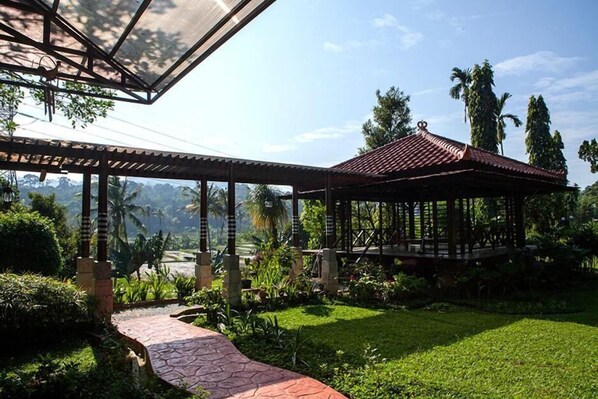 A covered outdoor area with a gazebo, a pathway, and lush greenery. - Villa Sawah Hotel and Resort (Megamendung)