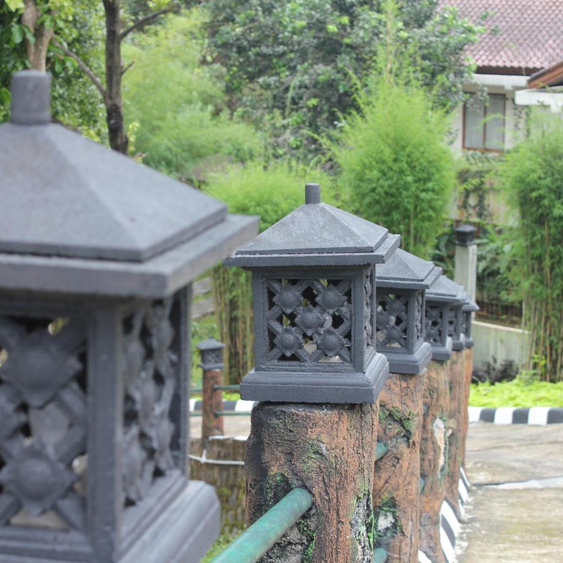 Una hilera de estructuras tradicionales tipo farol con diseños intrincados, frente a un fondo de vegetación exuberante y un edificio residencial.