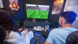 Ein Wohnzimmer mit Fernseher, einem kleinen Tisch mit einer Schale und Flaschen sowie einer Couch.