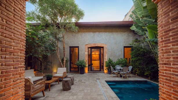 A brick building with a pool, outdoor seating, and a door leading to an interior space. - Casa del Orfebre Colonial Home in Zona Colonial , Pool & Private Patio (Santo Domingo)