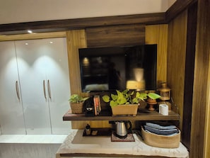 A modern living room with a flat-screen TV mounted on a wooden wall, a sofa, and a coffee table with decorative items.