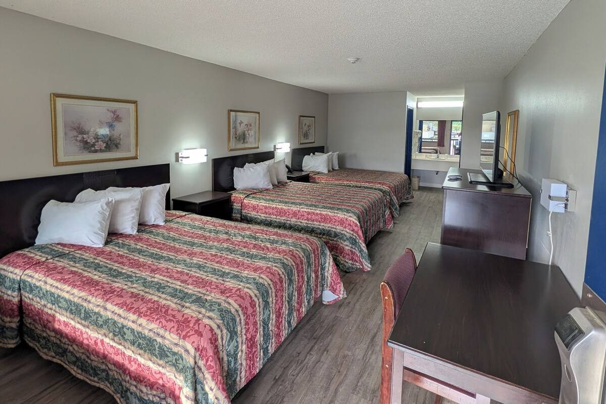 Una habitación de hotel con tres camas, un escritorio y una silla.