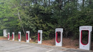 Una fila de estaciones de carga para vehículos eléctricos Tesla en un estacionamiento.