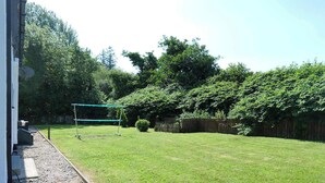 A backyard with a green netted play area, a small bush, and a wooden fence. - Private Ensuite Room Near Town With Quiet Garden (Letterkenny)