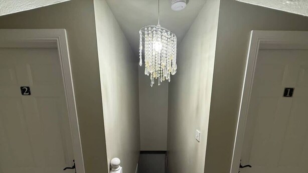 A narrow hallway with two doors, a staircase, and a chandelier. - Private Ensuite Room Near Town With Quiet Garden (Letterkenny)