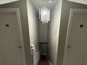 A narrow hallway with two doors, a staircase, and a chandelier. - Private Ensuite Room Near Town With Quiet Garden (Letterkenny)
