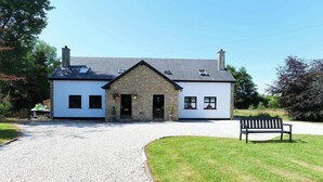 A two-story building with a stone facade, a gravel driveway, and a bench in the foreground. - Private Ensuite Room Near Town With Quiet Garden (Letterkenny)