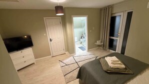 A hotel room with a bed, a TV, a door, and a view of the bathroom. - Private Ensuite Room Near Town With Quiet Garden (Letterkenny)