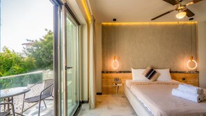 Un dormitorio con cama, ventilador de techo, mesita de noche y vistas al exterior.