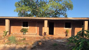 Un edificio de ladrillo con varias puertas y ventanas, rodeado de una zona de grava con macetas.