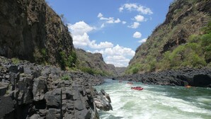 Un río con rápidos, rodeado de acantilados rocosos y vegetación escasa.