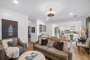 A modern living room with a sofa, coffee table, and a dining area with chairs and a table.