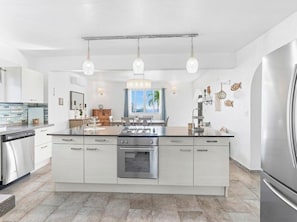 A modern kitchen with a central island, stainless steel appliances, pendant lighting, and a view of the outdoors. - Villa Esperanza Ocean View Villa |Private Pool | Gated Community | Walk to Beach (Dawn Beach)