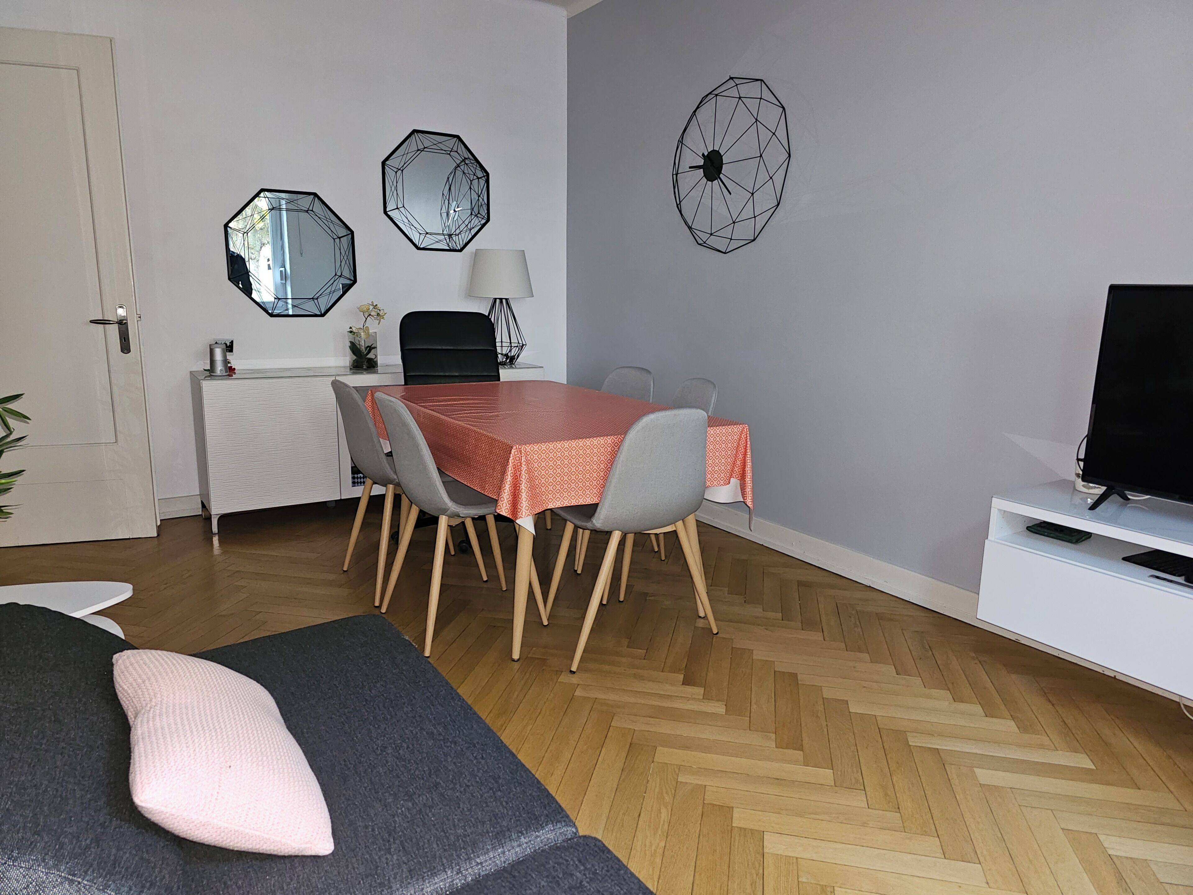 Et spiseområde med et bord, stole, et fjernsyn og en sofa.