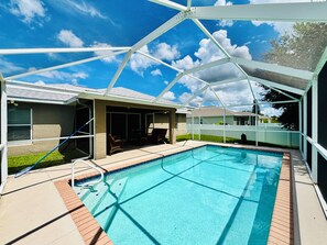 Una piscina con superficie d'acqua cristallina e azzurra, circondata da un portico coperto con sedie e un tavolo.