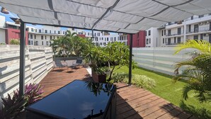 Ein überdachter Außenbereich mit Holzterrasse, Liegestühlen und Kübelpflanzen.