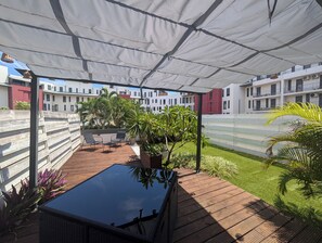 A covered outdoor area with a wooden deck, lounge chairs, and potted plants. - T2 Les portes du lagon, Saint-Pierre waterfront (Saint-Pierre)