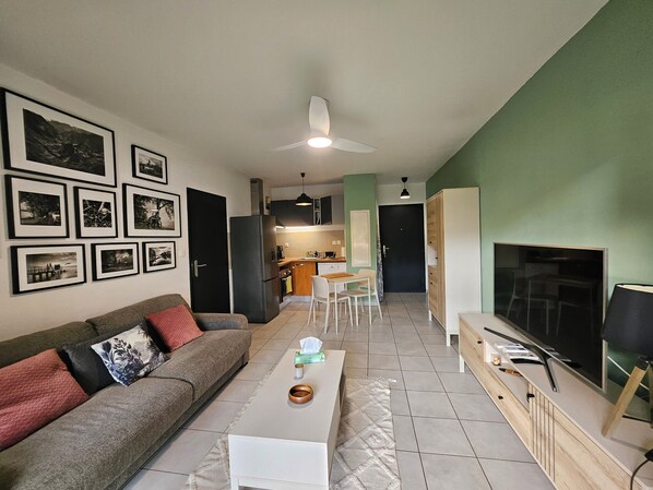 A living room with a sofa, coffee table, TV, and framed pictures on the wall.