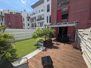 A rooftop patio with outdoor furniture, a small garden area with plants, and a view of adjacent buildings.
