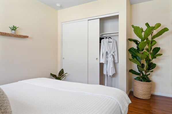 Un dormitorio con cama, armario y planta en maceta.