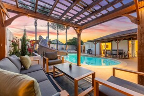 Zona de piscina con un espacio de descanso techado, un tobogán y una piscina.