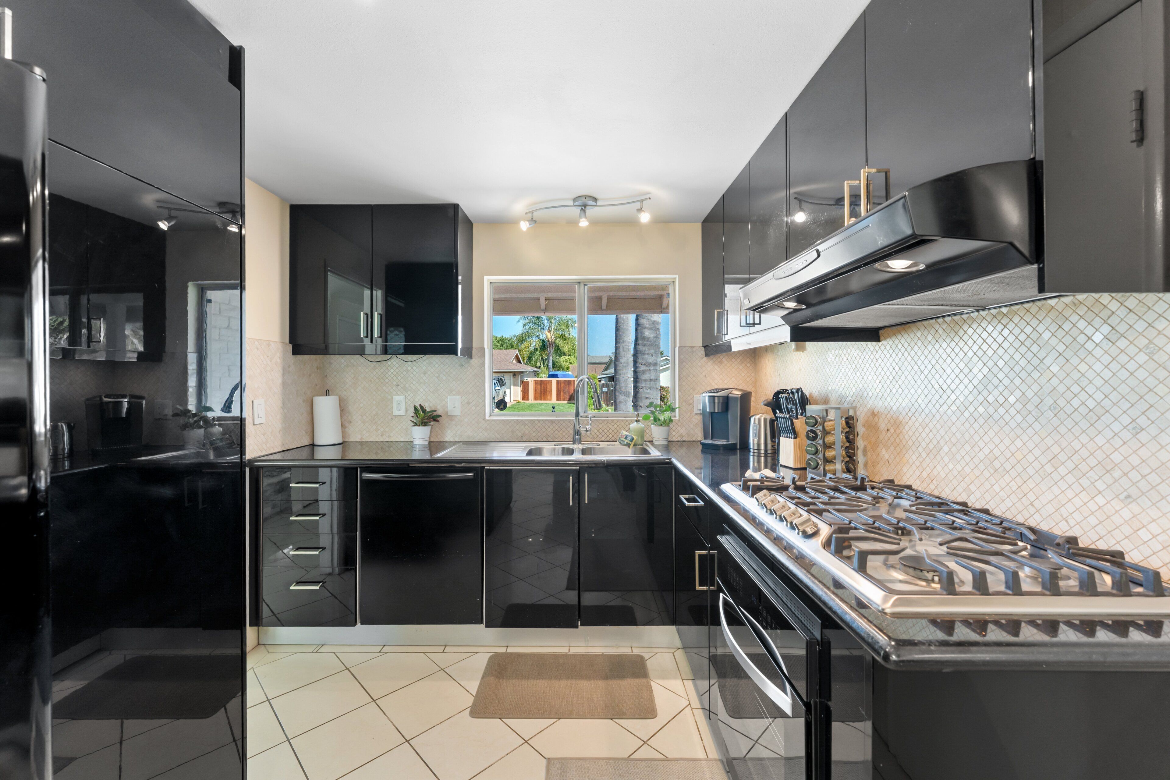 Une cuisine moderne avec des meubles noirs, une cuisinière en acier inoxydable et une fenêtre offrant une belle vue.