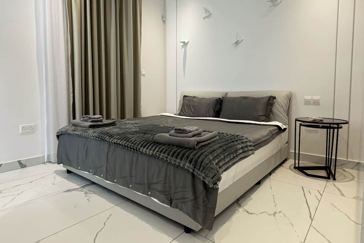 Un dormitorio moderno con una cama, una mesita redonda pequeña y una pared con un mural de pájaros.
