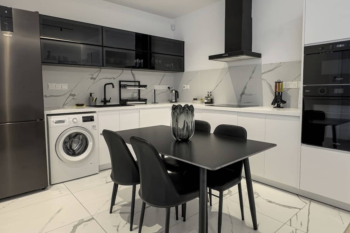Una cocina moderna con lavadora integrada, una mesa de comedor con sillas y una campana extractora negra.