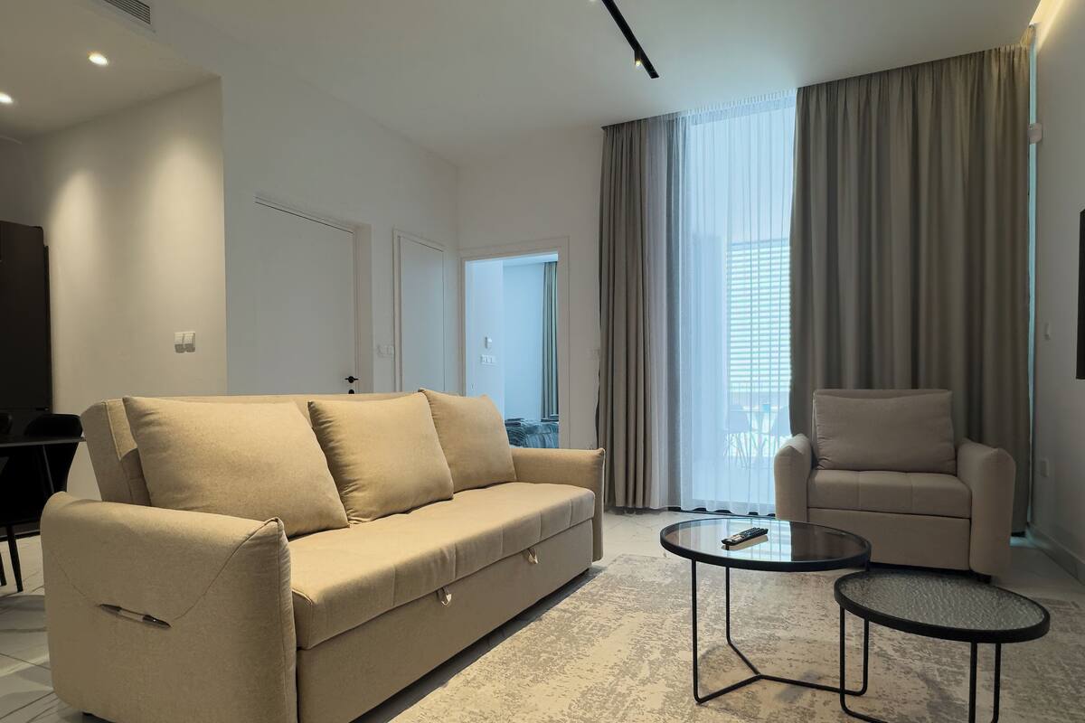 Una sala de estar moderna con un sofá, un sillón y dos mesas de centro.