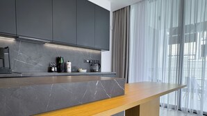 Eine moderne Küche mit Marmorarbeitsplatte, einer Holzbank und grauen Schränken.