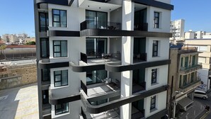 Ein mehrgeschossiges Wohngebäude mit Balkonen, großen Fenstern und einem Parkplatz.