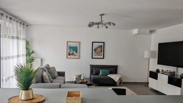 A modern living room with a grey sofa, a coffee table, a TV, and a ceiling fan. - House near Versailles & Paris with parking (Louveciennes)