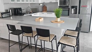 A modern kitchen with a central island, bar stools, a microwave, a toaster, and a refrigerator. - House near Versailles & Paris with parking (Louveciennes)