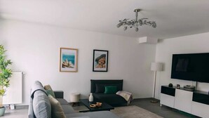 A modern living room with a sofa, a bed, a TV, and two framed pictures on the wall. - House near Versailles & Paris with parking (Louveciennes)