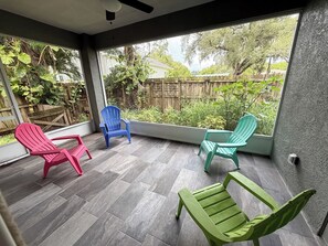 A covered patio with four chairs, a view of a backyard, and a wooden fence. - Superb 2-bedroom house with AC in sunny Sarasota (Sarasota)