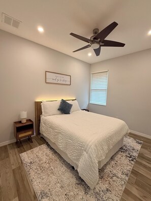 A bedroom with a bed, a nightstand, a ceiling fan, a window with blinds, and a framed quote on the wall. - Superb 2-bedroom house with AC in sunny Sarasota (Sarasota)