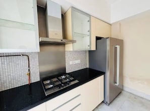 Una cocina con estufa a gas, armarios, refrigerador y salpicadero de azulejos.