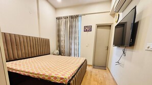 Ein Schlafzimmer mit einem Bett, einem Fernseher, einer Tür und einem Vorhang.