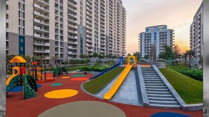 Ein Spielplatz mit Rutschen und Klettergerüsten, umgeben von Hochhäusern.