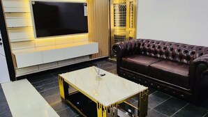 A modern living room with a flat-screen TV, a leather sofa, and a coffee table. - Nestvier apartment (Abuja)