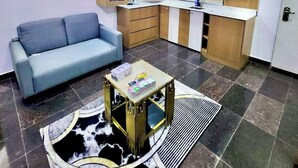 A compact living space with a sofa, a coffee table, a kitchen area, and a dining table. - Nestvier apartment (Abuja)