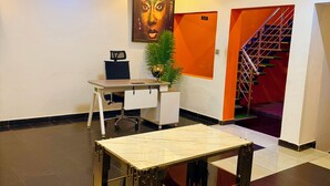 A hotel lobby with a reception desk, a large painting, a staircase, and a modern light fixture. - Nestvier apartment (Abuja)