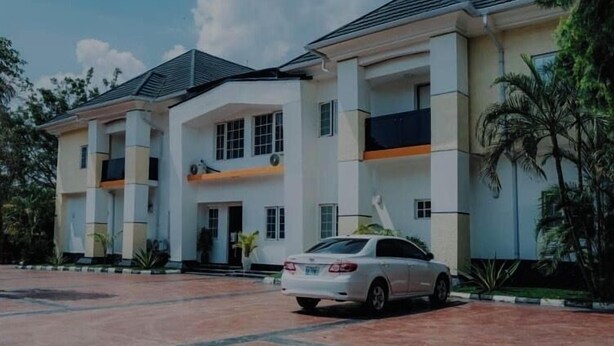 A multi-story building with a car parked in front. - Nestvier apartment (Abuja)
