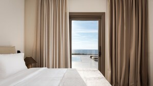 A hotel room with a bed, curtains, and a view of the sea. - Beach House Houlakia Mykonos (Mykonos)